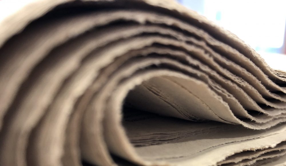 Das Bild zeigt dicke Zeitung, die zusammengerollt ist.